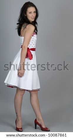 Woman wearing retro 1950's style white dress with red belt and red shoes