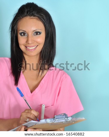 Beautiful young woman with friendly smile wearing pink scrubs while holding a clip board