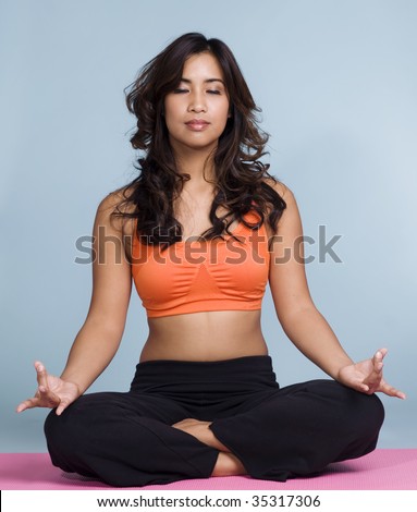 Attractive woman doing Lotus yoga pose in studio setting