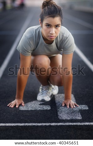 Young woman in start position on running track