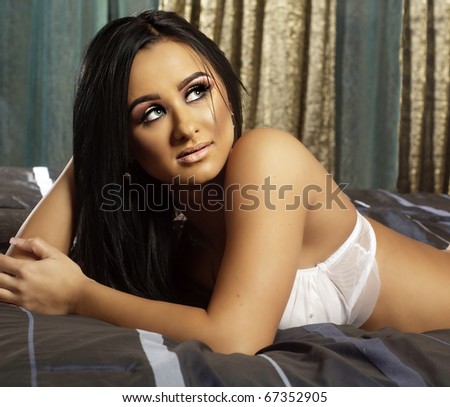 Beautiful young woman lying in bed with face turned and looking upward.