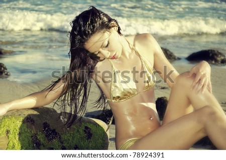 Beautiful woman posing in golden bikini on Malibu Beach in California