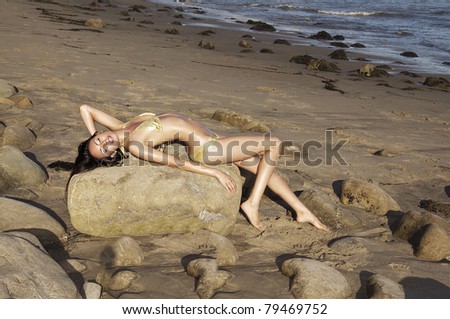 Beautiful woman lying on rock at a beach