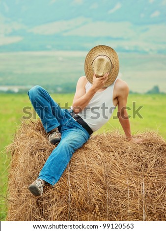 farmer sit on a haystack and hides the face