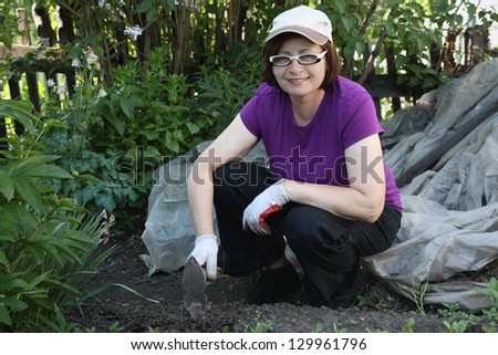 The woman the gardener in a garden weeding vegetables