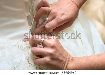 Girlfriends of the bride help to put on a wedding dress