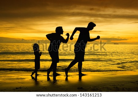 Silhouette of two man and his daughter play around during sunset.