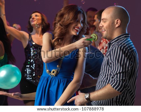 sexy, young couple having drinks on the dancefloor, in a night club