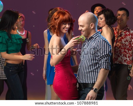 sexy, young couple having drinks on the dancefloor, in a night club