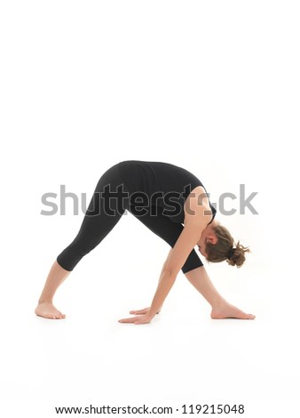 side view of young woman in yoga posture, face obscuredm dressed in blak, on white backgrond