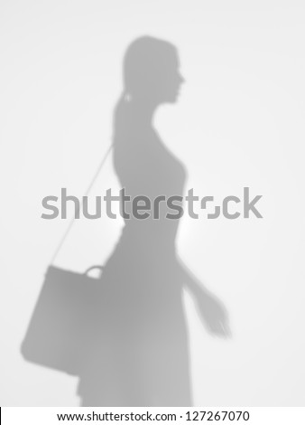 side view of young business woman with shoulder bag, walking behind a diffuse surface