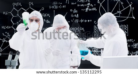 close-up of three people conducting a laboratory experiment using laboratory transparent tools and a blackboard with formulas  on the background