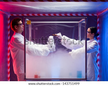 two scientists, a man and a woman, mixing chemicals in a sterile chamber labeled as bio hazardous filled with white steam, the woman holding a brown bottle, in a containment tent