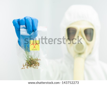 person in protective suit and gas mask holding a bag with a sample of contaminated crop