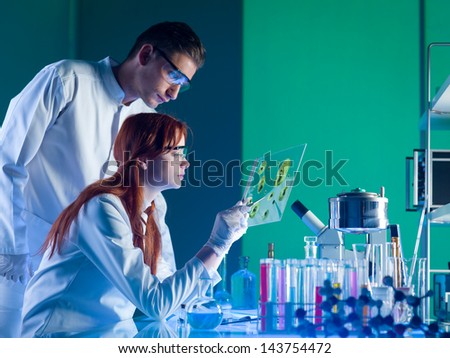 side view of two young caucasian researchers studying a sample in a laboratory