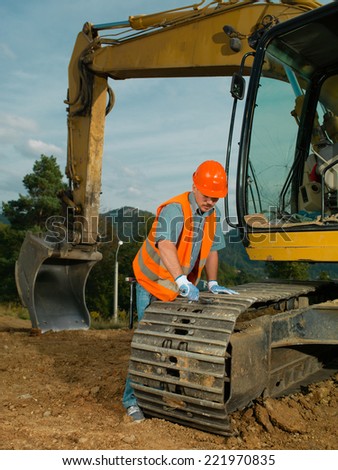 male construction worker repairing excavator track