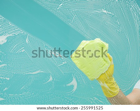 man washing window, clearing out detergent with rag