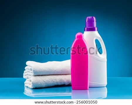 white towels, liquid laundry detergent and softener against blue background