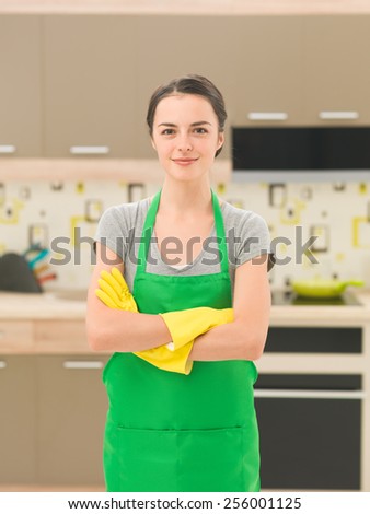 young caucasian smiling woman wearing apron and rubber gloves, standing in kitchen