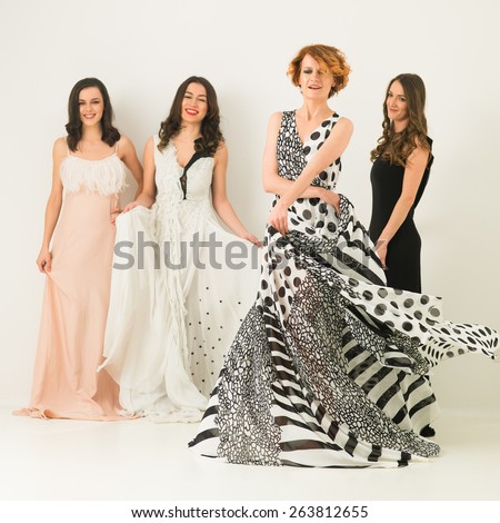 beautiful caucasian women in cocktail dresses posing together, dancing and having fun