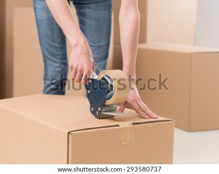 close-up of female sealing cardboard box with adhesive tape