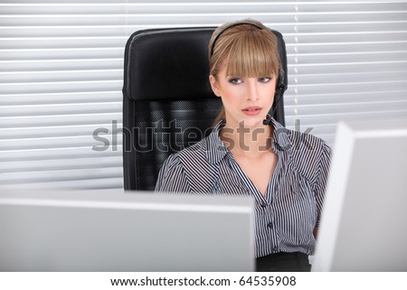 Secretary with headphone and multiple monitors talking