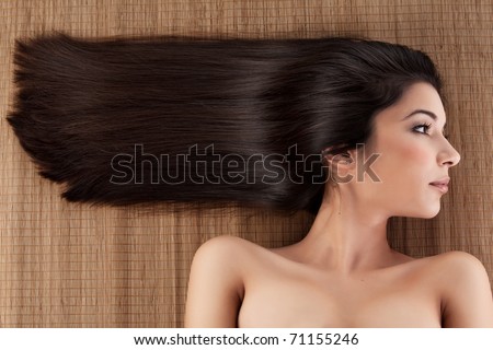 a close-up profile portrait of a young woman, laying on a spa mat. her hair is laying strait, in a horizontal direction.