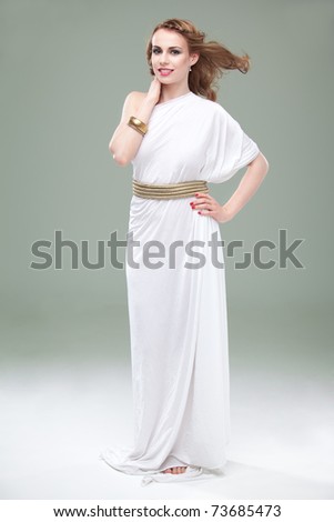 a studio portrait of a beautiful young woman, wearing a long, white, ancient greek inspired dress, smiling, with wind blowing in her hair.