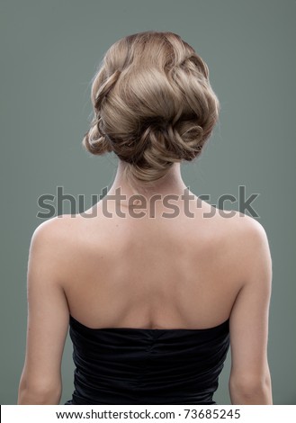 a head and shoulders image of a young woman, from the back. her hair is long and blonde and she is showing an interesting, wavy hairstyle.