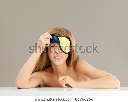beauty portrait of blonde woman peeping from a sleeping mask, smiling