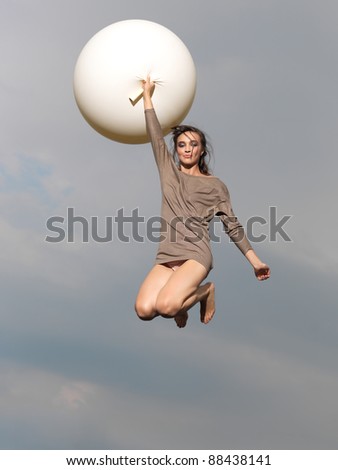 happy, young woman jumping with big, white balloon