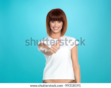 beautiful, young woman smiling and showing an ok sign with her hand, on blue background