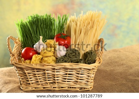 Raw green and yellow tagliatelle paglia e fieno (straw and hay) with raw tomatoes and garlic bulbs (Selective Focus, Focus on the ingredients in the front)