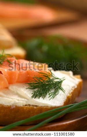 Canape of smoked salmon and cream cheese on wholewheat bun garnished with dill, chives on the side (Selective Focus, Focus on the front of the dill and on the front of the salmon on the left)