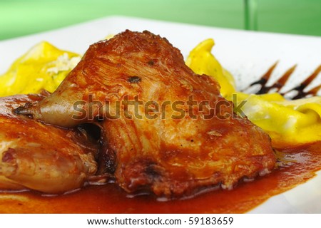 Main Dish: Guinea pig meat with gravy and tortellini on green background (Selective Focus)