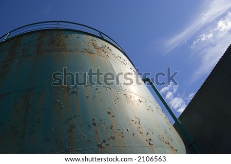 Peeling paint on an industrial tank against the sky