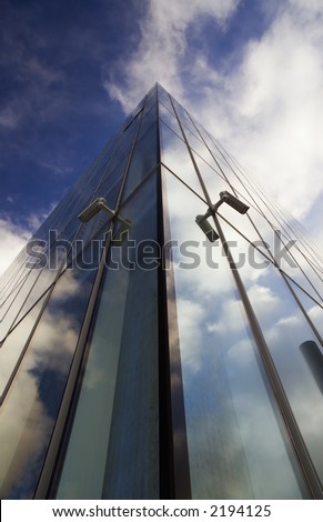 Corner of glass faced office building reflecting sky