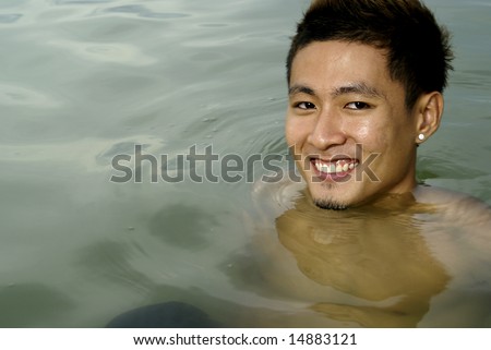 Smiling asian man in sea water