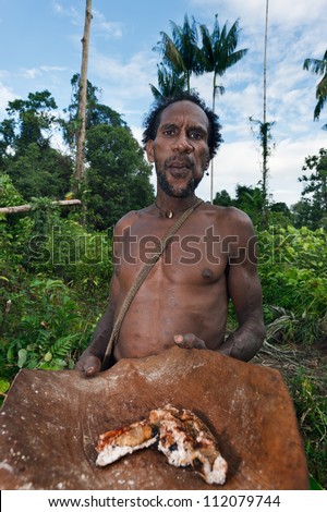 ONNI VILLAGE, NEW GUINEA, INDONESIA - JUNY 24: The Korowai man it suggests to be treated cooked saga worms. June 24, 2012 in Onni Village, New Guinea, Indonesia