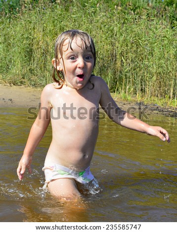 Happy smiling Little girl in water and spray on sunny day