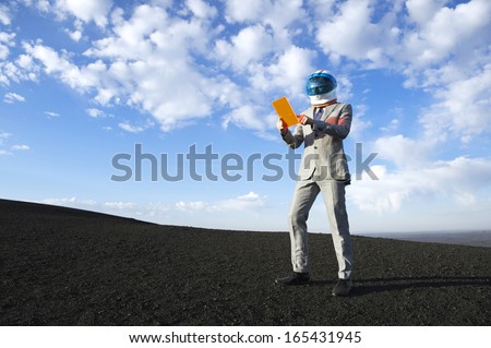 Businessman astronaut using futuristic tablet on dramatic lunar landscape
