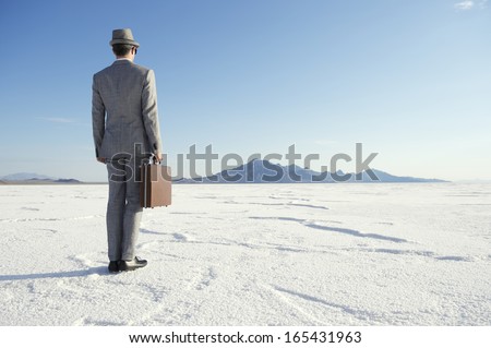 Traveling businessman standing ready with briefcase looking out on horizon