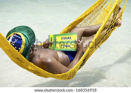 Brazilian soccer fan relaxing in beach hammock with two tickets to the final football match