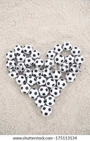 Football love heart made with soccer balls Valentines Day message on sand beach