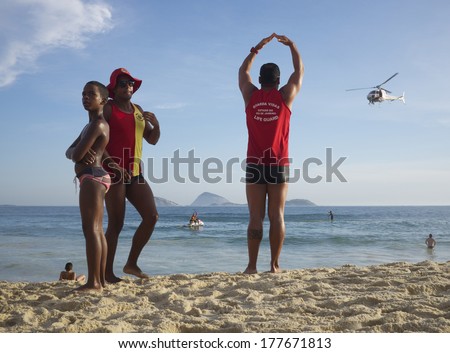 RIO DE JANEIRO, BRAZIL - JANUARY 15, 2014: Lifeguards on Ipanema Beach give the all clear signal to a search and rescue helicopter after a missing person was found.