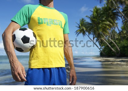 Football player in Brasil t-shirt holding soccer ball on remote beach in Nordeste Bahia Brazil