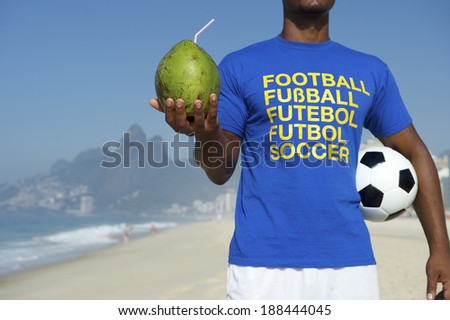 Brazilian soccer player in multi language message t-shirt holding football and drinking coconut Rio de Janeiro