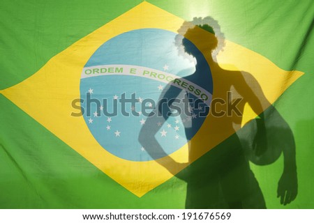 Shadow silhouette of Brazilian holding football in the sun against Brazil flag