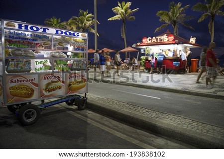RIO DE JANEIRO, BRAZIL - JANUARY 19, 2014: Mobile hot dog stand parks in front of beach kiosk in a typical sunset scene on Ipanema Beach.