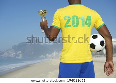 Champion Brazilian soccer player holding trophy and football in 2014 shirt Ipanema Beach Rio de Janeiro Brazil